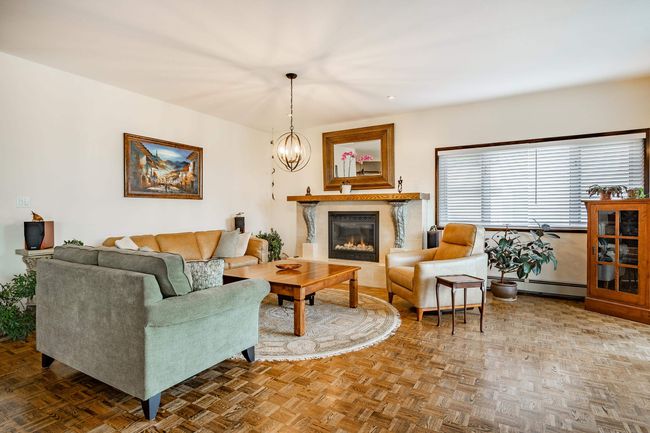 Living area with a glass covered fireplace, baseboard heating, and a chandelier | Image 6
