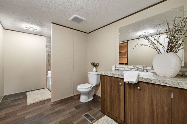 Bathroom with wood finished floors, visible vents, toilet, vanity, and a textured ceiling | Image 25