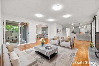 Spacious living room with access to outdoor patio. The dining area and kitchen are in the back ground. | Image 3