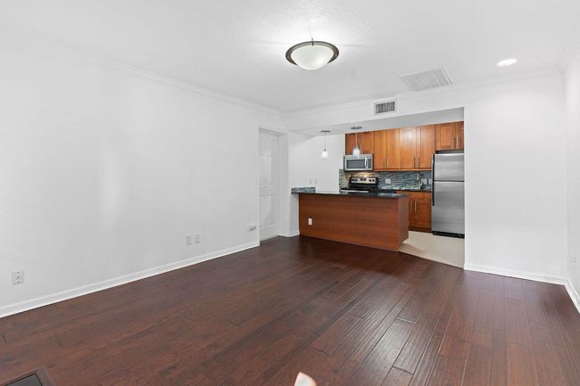 Kitchen featuring visible vents, brown cabinets, dark countertops, appliances with stainless steel finishes, and a peninsula | Image 16