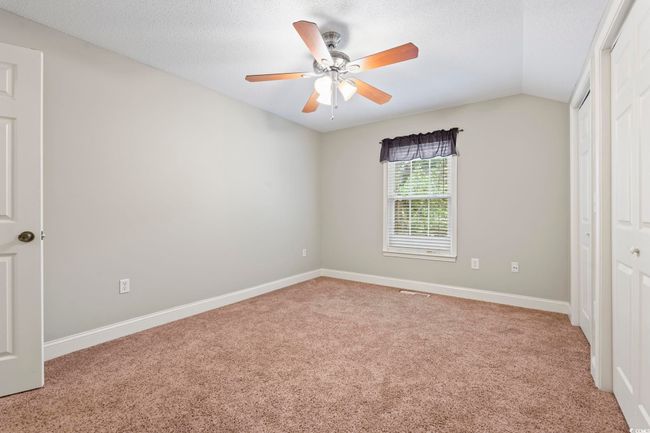 Unfurnished bedroom featuring carpet floors, a textured ceiling, vaulted ceiling, baseboards, and a ceiling fan | Image 30