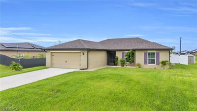 Ranch-style house with a garage, a front lawn, and solar panels | Image 1