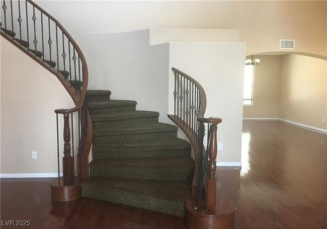 Staircase with wood finished floors, arched walkways, and a chandelier | Image 8
