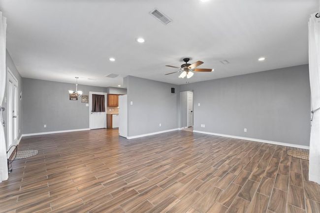 The open layout of the living area flows into a dining area. French doors provide natural light and access to the outdoors. | Image 12