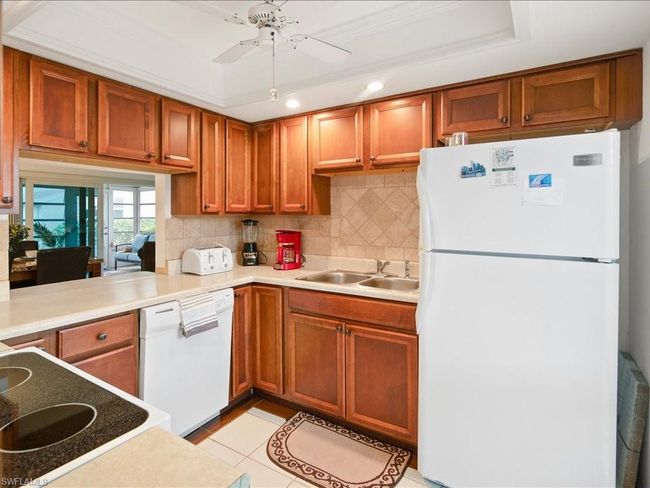 Kitchen with a sink, decorative backsplash, white appliances, and ceiling fan | Image 23