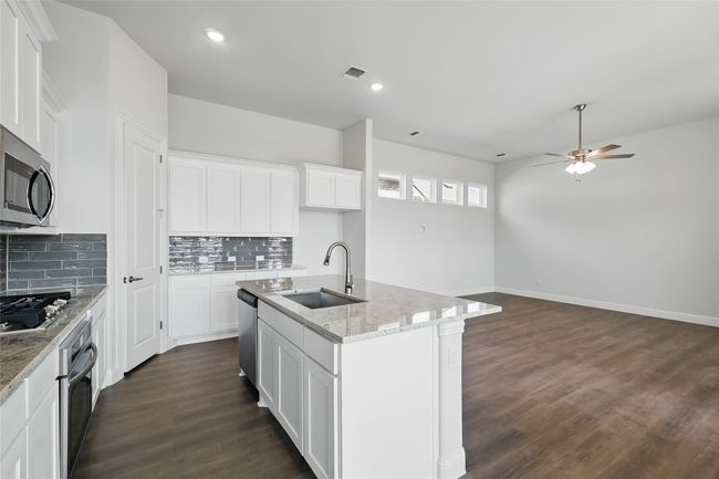 Kitchen with a ceiling fan, visible vents, dark wood finished floors, stainless steel appliances, and a sink | Image 4