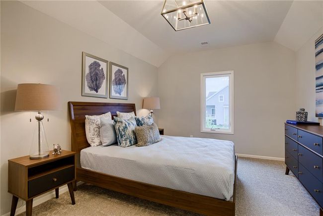 Carpeted bedroom with lofted ceiling and a notable chandelier | Image 42