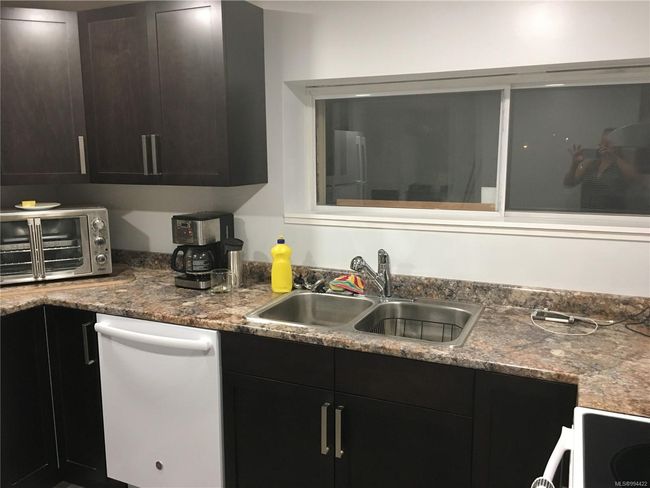 Kitchen with a sink, a toaster, white dishwasher, and electric range | Image 28