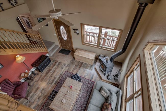 Living area featuring ceiling fan, stairway, healthy amount of natural light, a high ceiling, and wood finished floors | Image 39