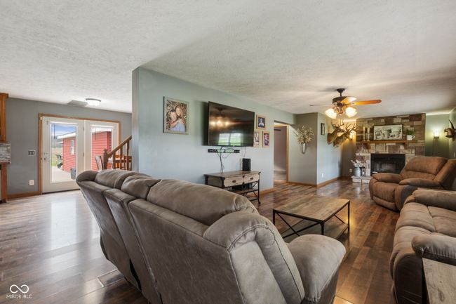living room featuring a textured ceiling, ceiling fan, wood-type flooring, and a stone fireplace | Image 13