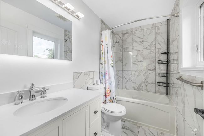 Bathroom with shower / tub combo, toilet, marble look tiles, and vanity | Image 26