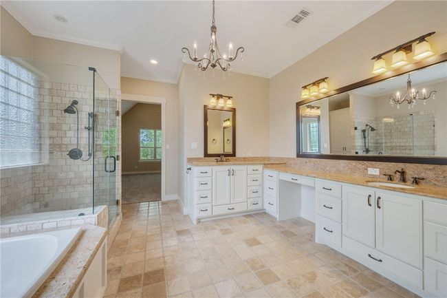 Full bathroom featuring a chandelier, a stall shower, ornamental molding, vanity, and a bathtub | Image 25