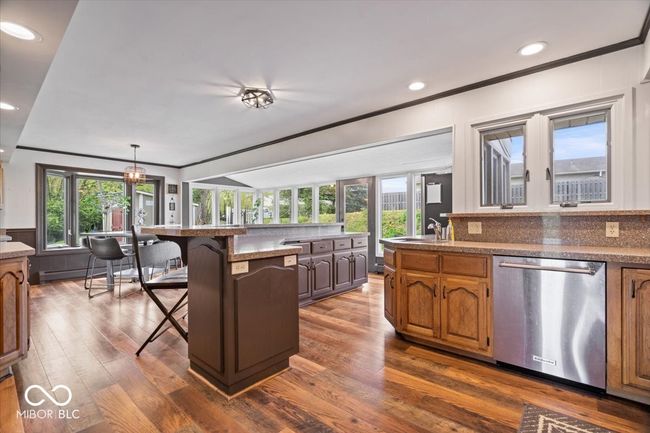 kitchen with stainless steel dishwasher, a kitchen bar, ornamental molding, dark wood finished floors, and recessed lighting | Image 18