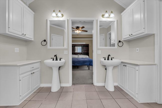 Bathroom featuring crown molding, ceiling fan, baseboards, tile patterned flooring, and two sinks | Image 19