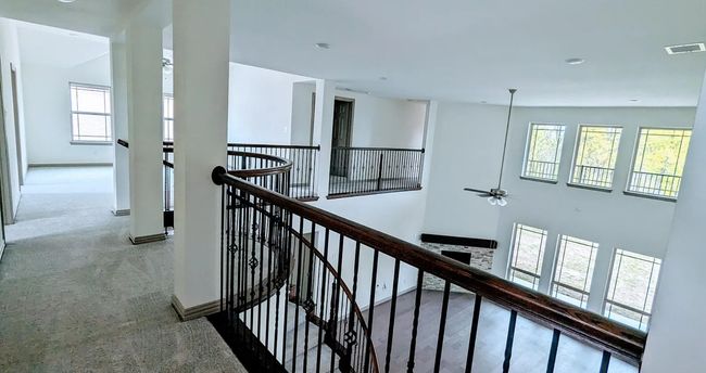 Corridor with baseboards, visible vents, an upstairs landing, and a healthy amount of sunlight | Image 4