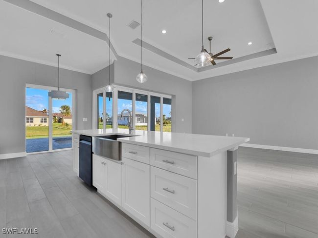 Kitchen with ceiling fan, a raised ceiling, light countertops, a kitchen island with sink, and healthy amount of natural light | Image 11