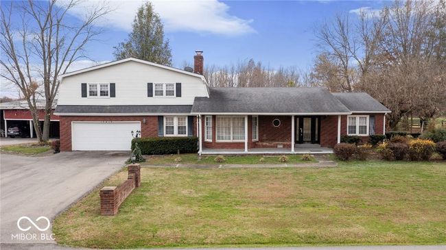 view of front of property with covered porch, brick siding, an attached garage, and driveway | Image 37