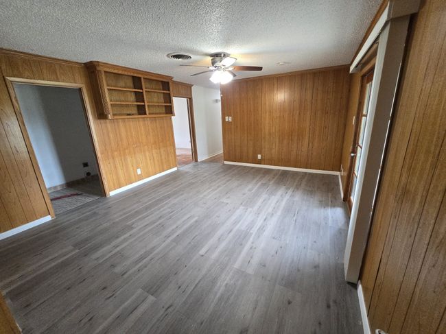 Unfurnished bedroom featuring wooden walls, wood finished floors, a textured ceiling, and a ceiling fan | Image 19