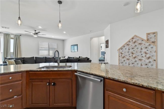 Kitchen featuring a sink, visible vents, open floor plan, brown cabinets, and dishwasher | Image 22