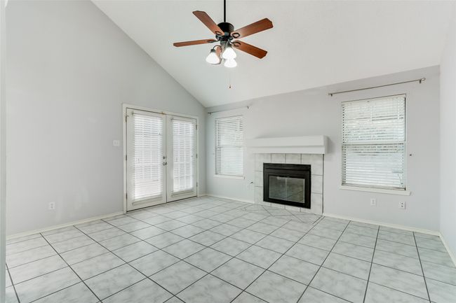 Unfurnished living room featuring french doors, high vaulted ceiling, a ceiling fan, baseboards, and a tile fireplace | Image 10