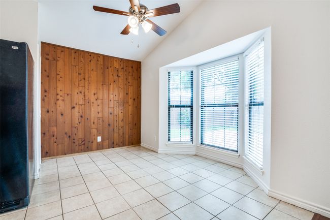 Dining room with patterned floors, wood walls, and high vaulted ceiling. Open to both the kitchen and living room area. | Image 9