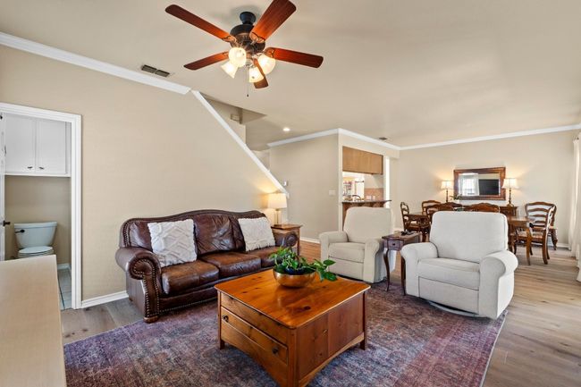 Living room with visible vents, crown molding, a ceiling fan, and wood finished floors | Image 7