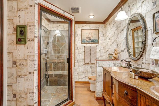 Keaton's Lodge private bathroom features fun wallpaper, double vanity with handforged copper sinks, custom tiled walk-in shower with bench, extra dressing area space | Image 28