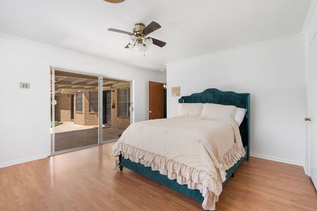 Primary Bedroom featuring access to outside, wood finished floors, crown molding, and a ceiling fan | Image 18