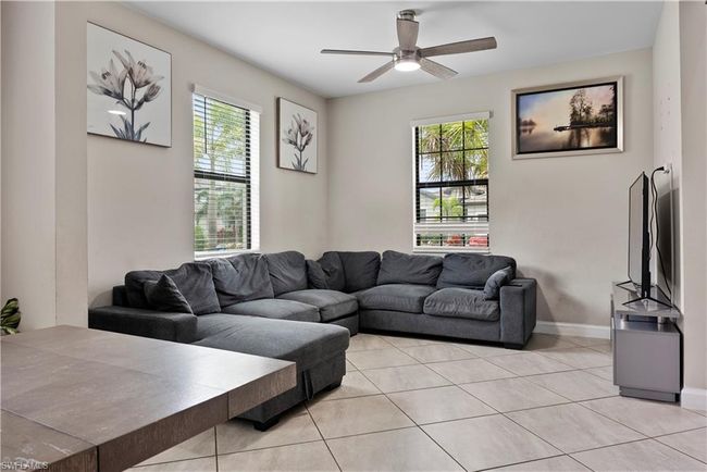 Living room featuring light tile patterned flooring, baseboards, and a ceiling fan | Image 7
