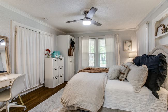 Bedroom featuring ornamental molding, a ceiling fan, a textured ceiling, dark wood-style floors, and a textured wall | Image 15