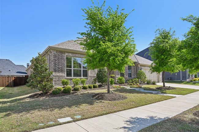 Obstructed view of property with brick siding, a garage, a shingled roof, and driveway | Image 4