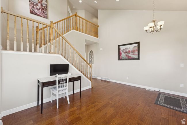 Living room featuring wood finished floors, stairs, a chandelier, recessed lighting, and a high ceiling | Image 8