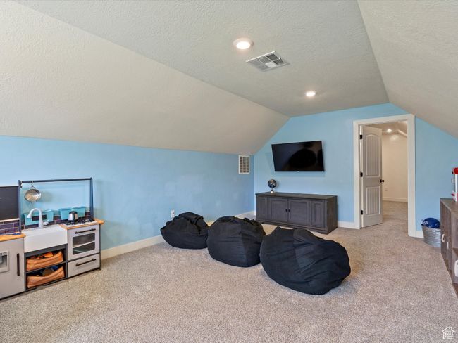 Additional living space featuring carpet flooring, vaulted ceiling, a textured ceiling, and baseboards | Image 23