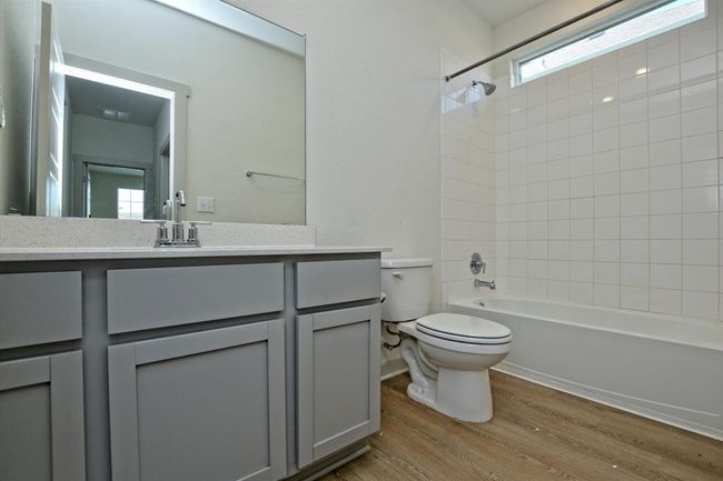 Bathroom with toilet, wood finished floors, vanity, and washtub / shower combination | Image 24