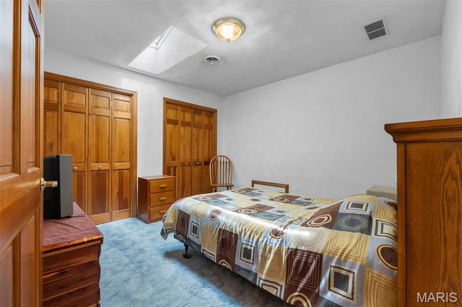 Carpeted bedroom with a skylight and multiple closets | Image 76