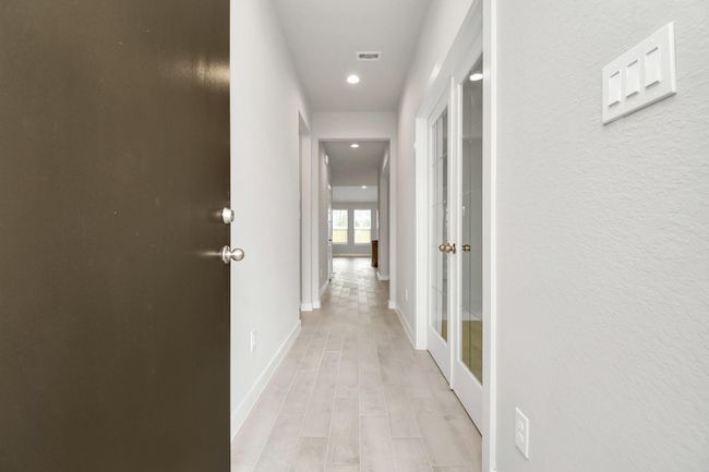 As you step into the threshold of this luxurious home, you'll soon be welcomed by an elegant glass door (to be installed), high ceilings, adorned with elegant wood-look tile flooring and oversized baseboards, and recessed lighting. Follow path of natural light from expansive windows ahead. | Image 6