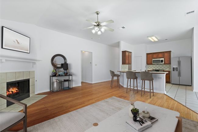 Living area with light wood-style floors, ceiling fan, and a tile fireplace | Image 9