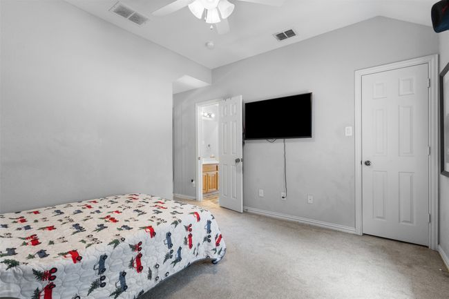 Bedroom with light colored carpet, lofted ceiling, baseboards, ceiling fan, and ensuite bathroom | Image 30