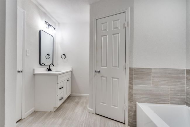 Bathroom featuring a garden tub, vanity, tile walls, and light wood-style flooring | Image 20