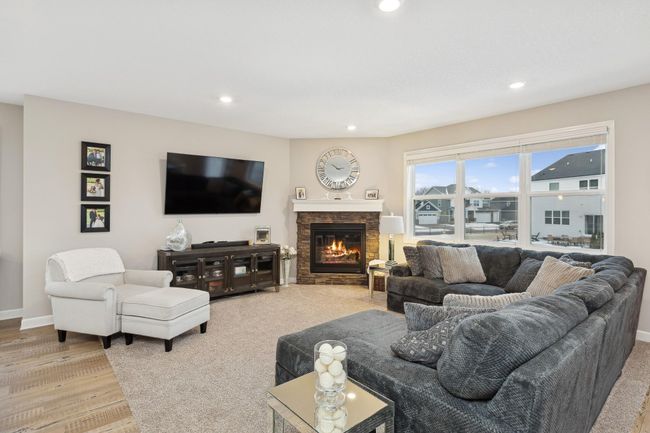 A gas fireplace with a stone surround serves as the focal point of the cozy family room. | Image 5