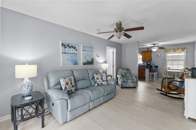 Living room featuring a ceiling fan, light wood-style floors, a textured ceiling, and baseboards | Image 4