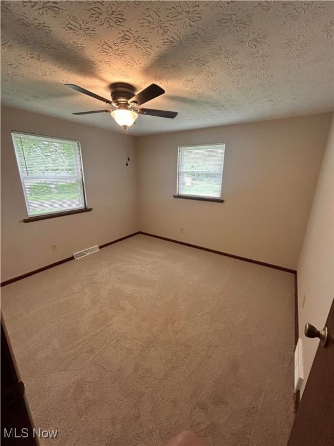 Unfurnished room with light colored carpet, a textured ceiling, baseboards, and a ceiling fan | Image 19