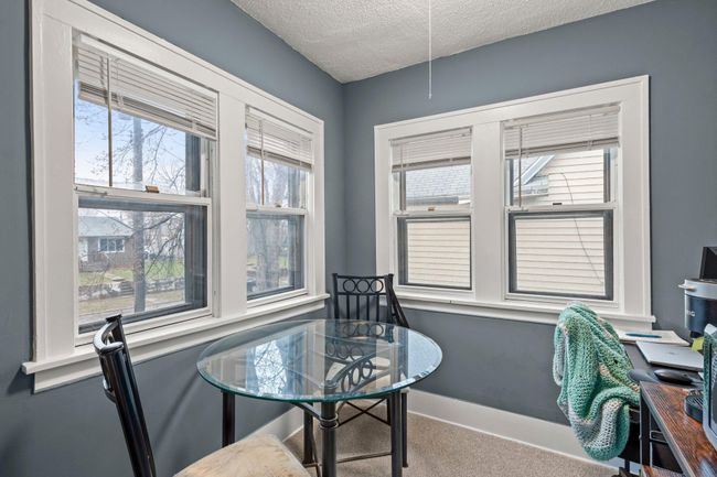 The dining room, located next to the kitchen, features carpeting and is lined with windows that fill the space with natural light — a perfect spot to enjoy a meal. | Image 6
