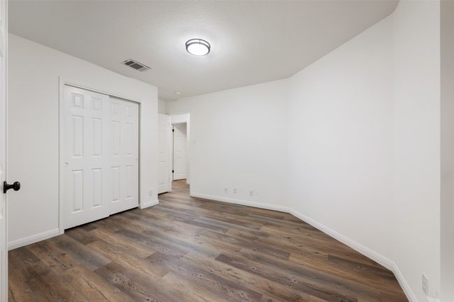 Unfurnished bedroom with dark wood finished floors and a closet | Image 12