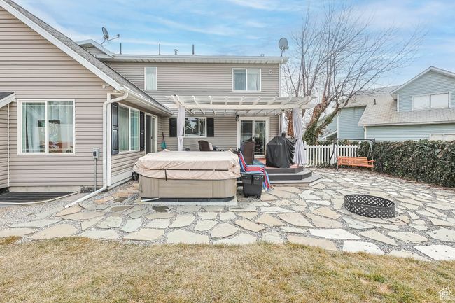 Back of house featuring a hot tub, a patio area, fence, a pergola, and a fire pit | Image 35
