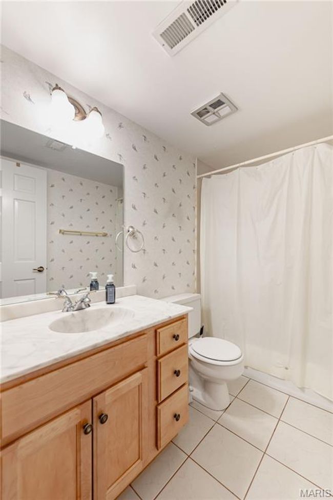 Full bathroom featuring wallpapered walls, vanity, tile patterned floors, and curtained shower | Image 44