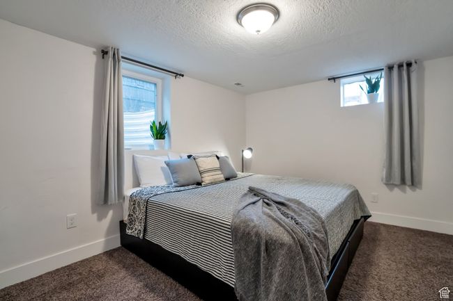 Bedroom featuring dark carpet, a textured ceiling, and baseboards | Image 11
