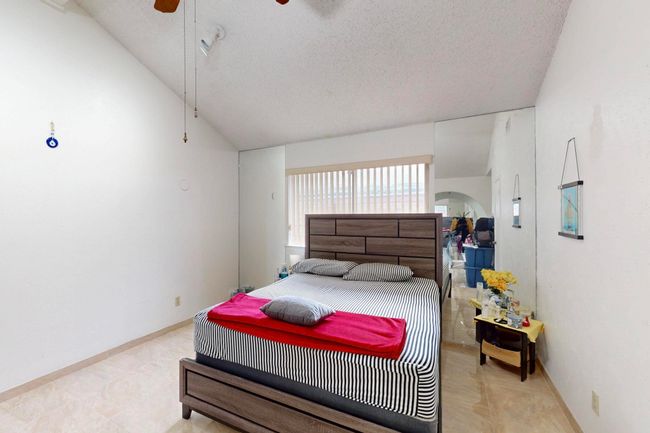 Bedroom with baseboards, lofted ceiling, a ceiling fan, and a textured ceiling | Image 16