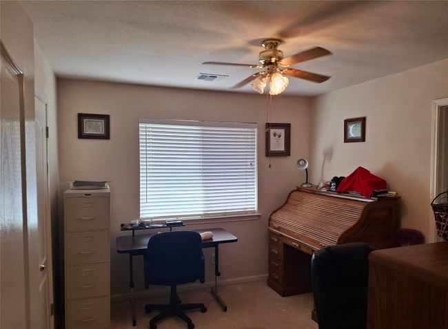 Carpeted office space with baseboards, visible vents, and a ceiling fan | Image 16