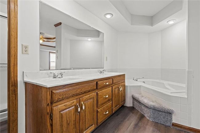 Bathroom with vanity, a raised ceiling, ceiling fan, wood-type flooring, and a relaxing tiled tub | Image 29